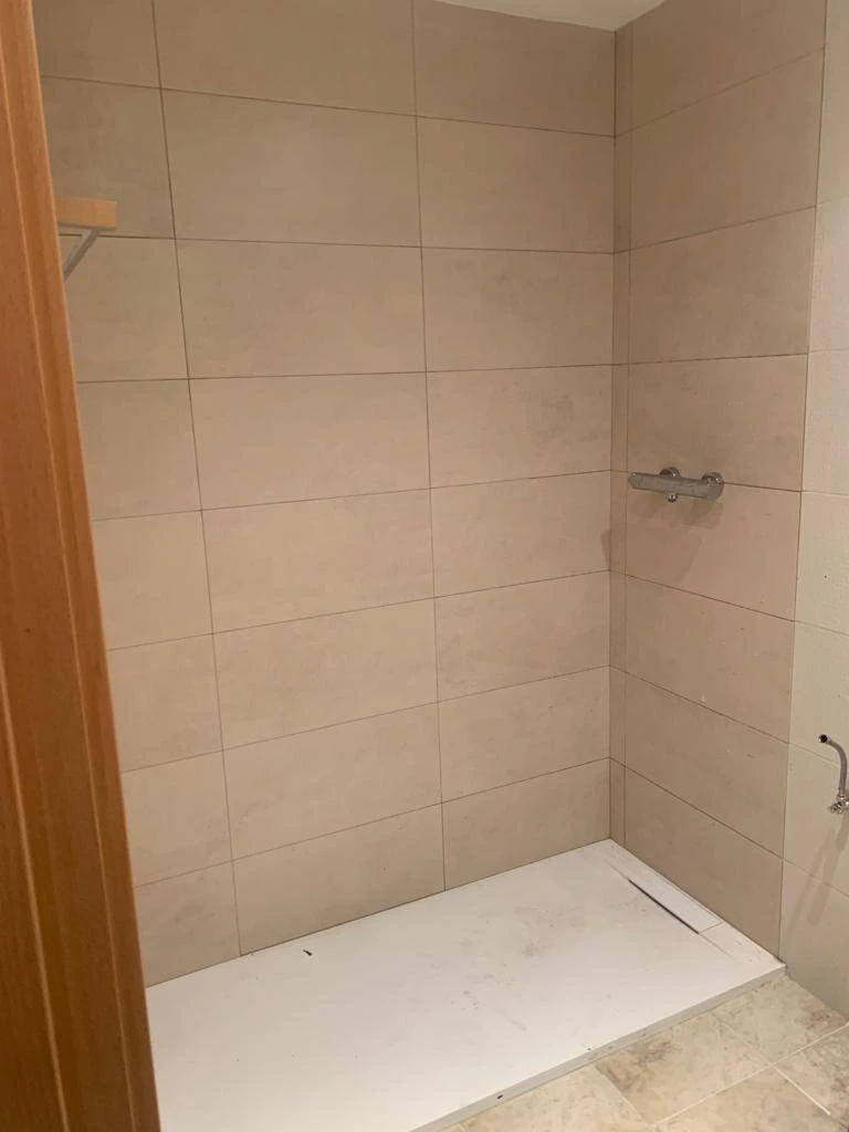 Reforma de baño con plato de ducha blanco y paredes alicatadas en tonos beige en Etxebarri