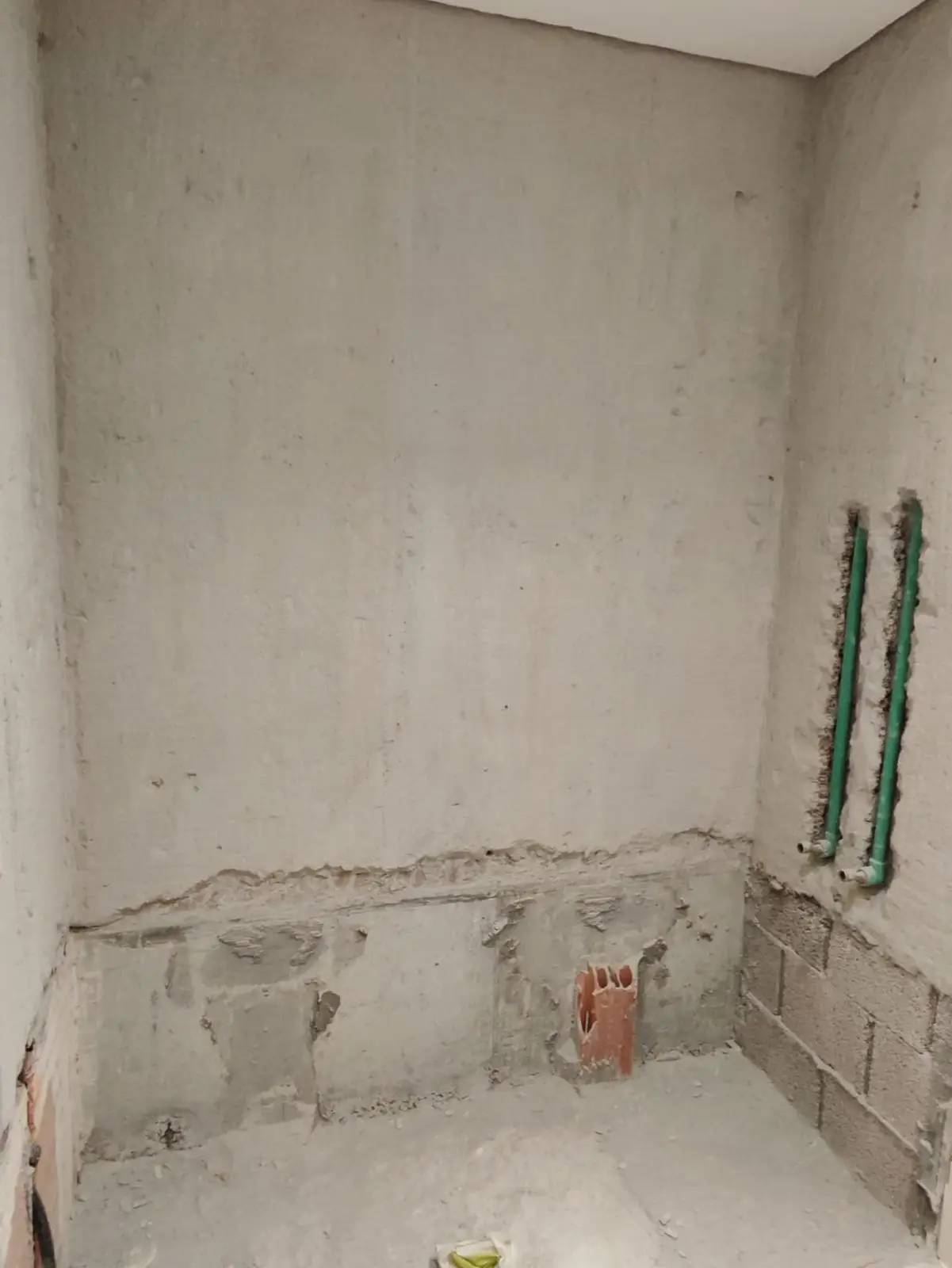Trabajos de fontanería con tuberías empotradas en pared de cemento durante una obra en Etxebarri
